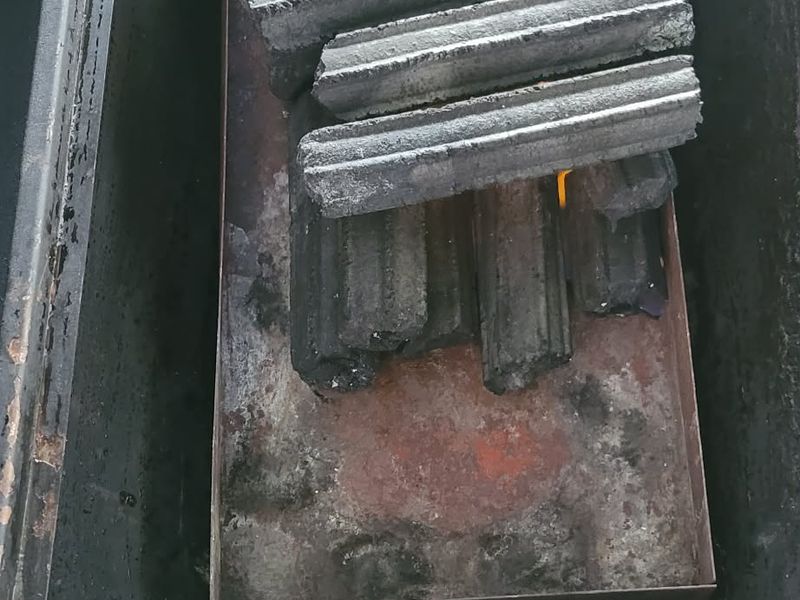 Sawdust briquettes alight with flame drawing up through the bars